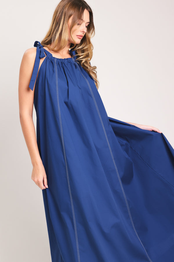 Woman wearing a blue midi dress with bow straps and pockets | Flying Tomato
