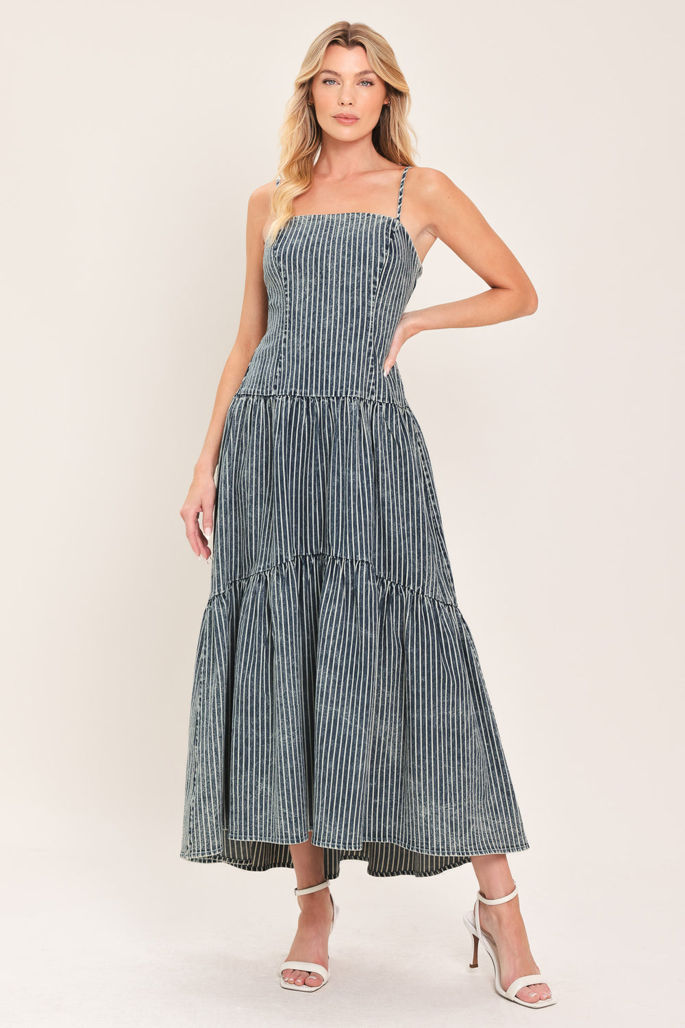 Woman wearing a blue striped washed denim midi dress featuring straight neckline, straps, drop waistline, single tier and back zipper closure | Flying Tomato
