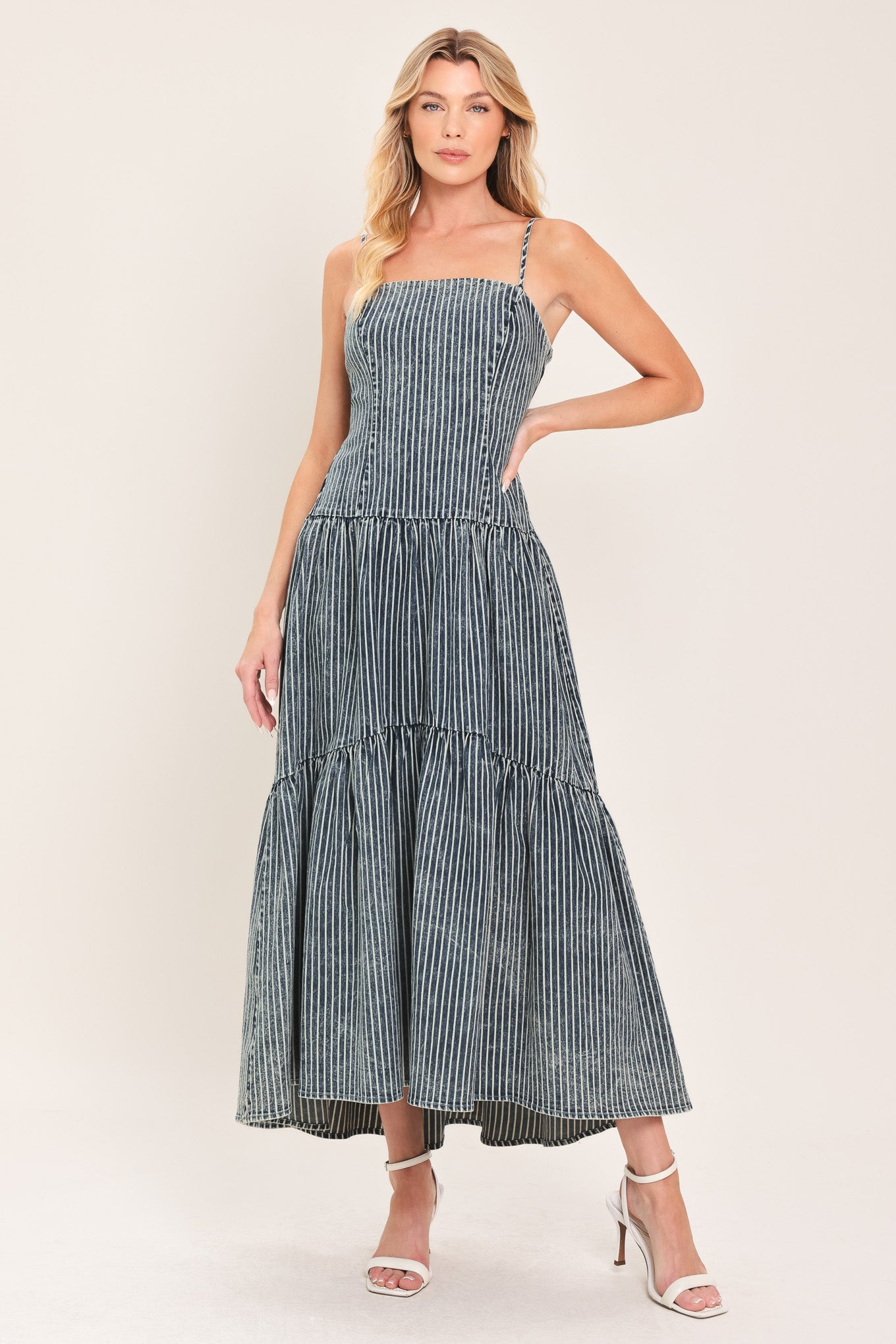 Woman wearing a blue striped washed denim midi dress featuring straight neckline, straps, drop waistline, single tier and back zipper closure | Flying Tomato