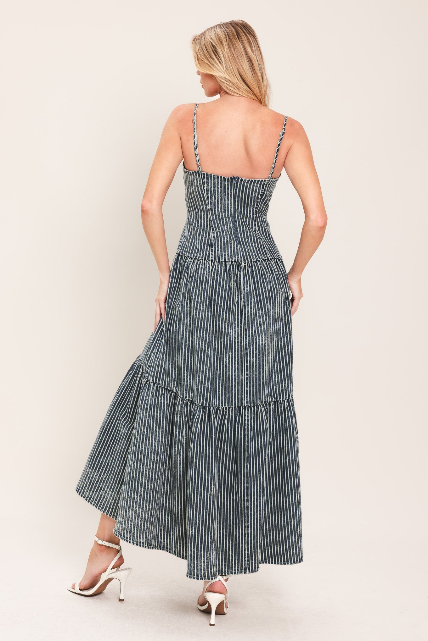 Woman wearing a blue striped washed denim midi dress featuring straight neckline, straps, drop waistline, single tier and back zipper closure | Flying Tomato
