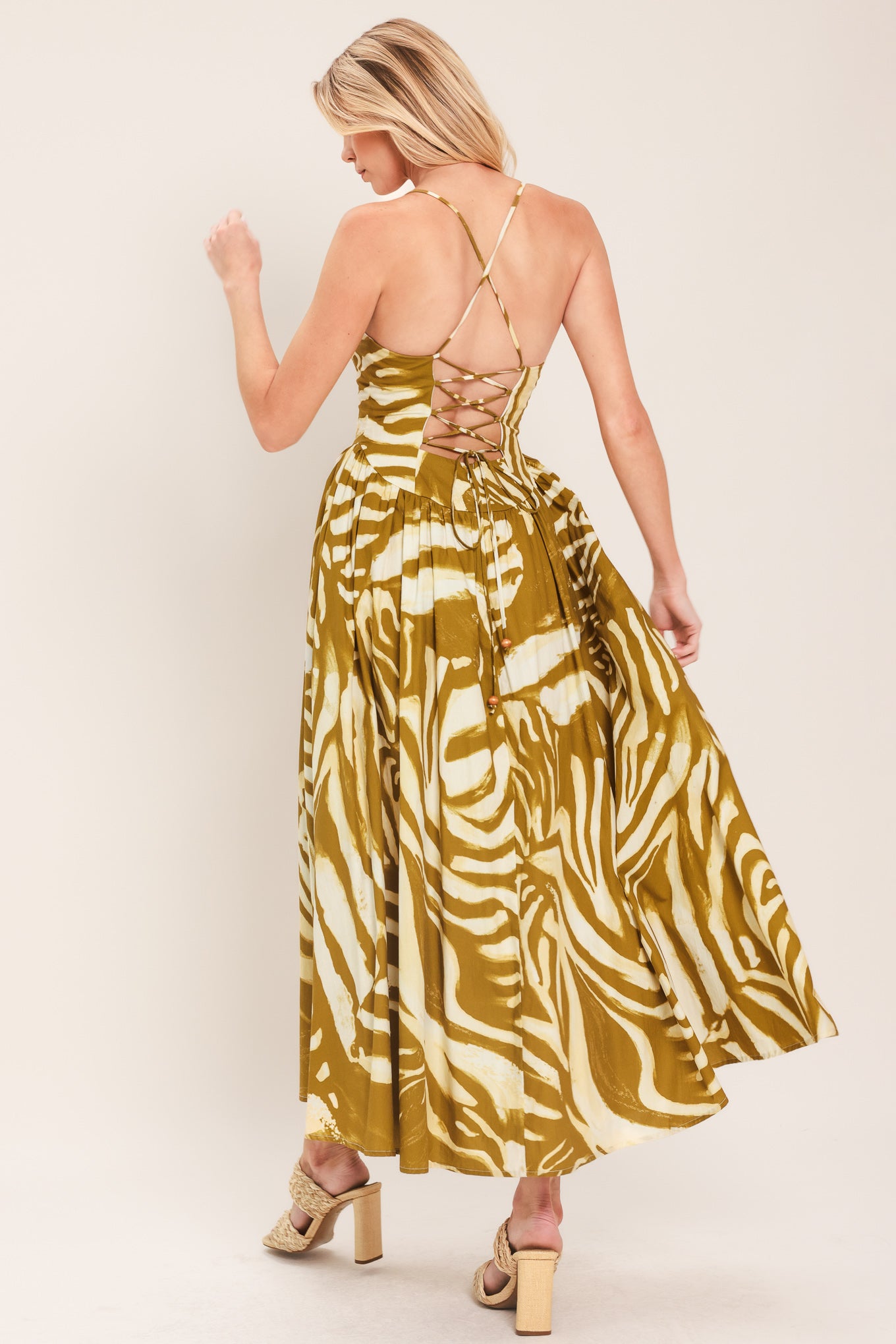 Woman wearing a mustard yellow and white patterned midi dress featuring bustier top, full skirt, bare back with lace up tie and zipper closure | Flying Tomato