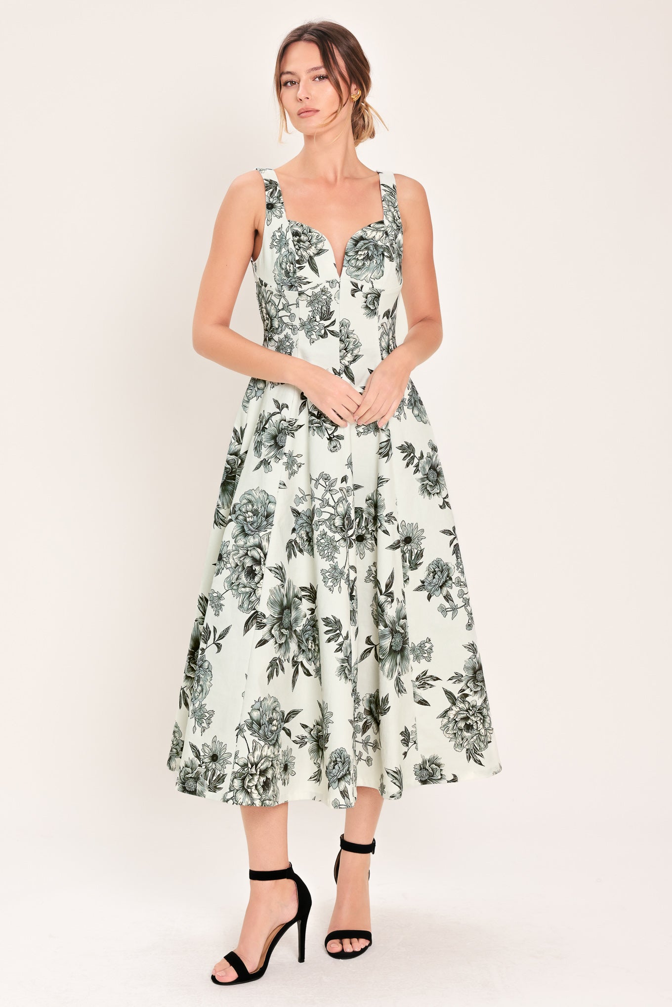 Woman wearing a black and white floral midi dress featuring sweetheart neckline, straps, circle skirt and back zipper closure | Flying Tomato