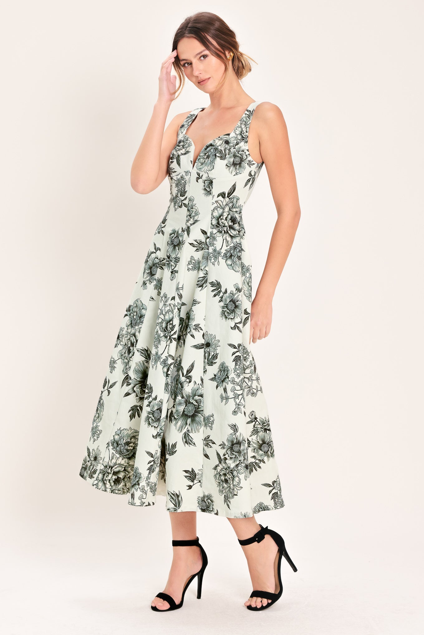 Woman wearing a black and white floral midi dress featuring sweetheart neckline, straps, circle skirt and back zipper closure | Flying Tomato