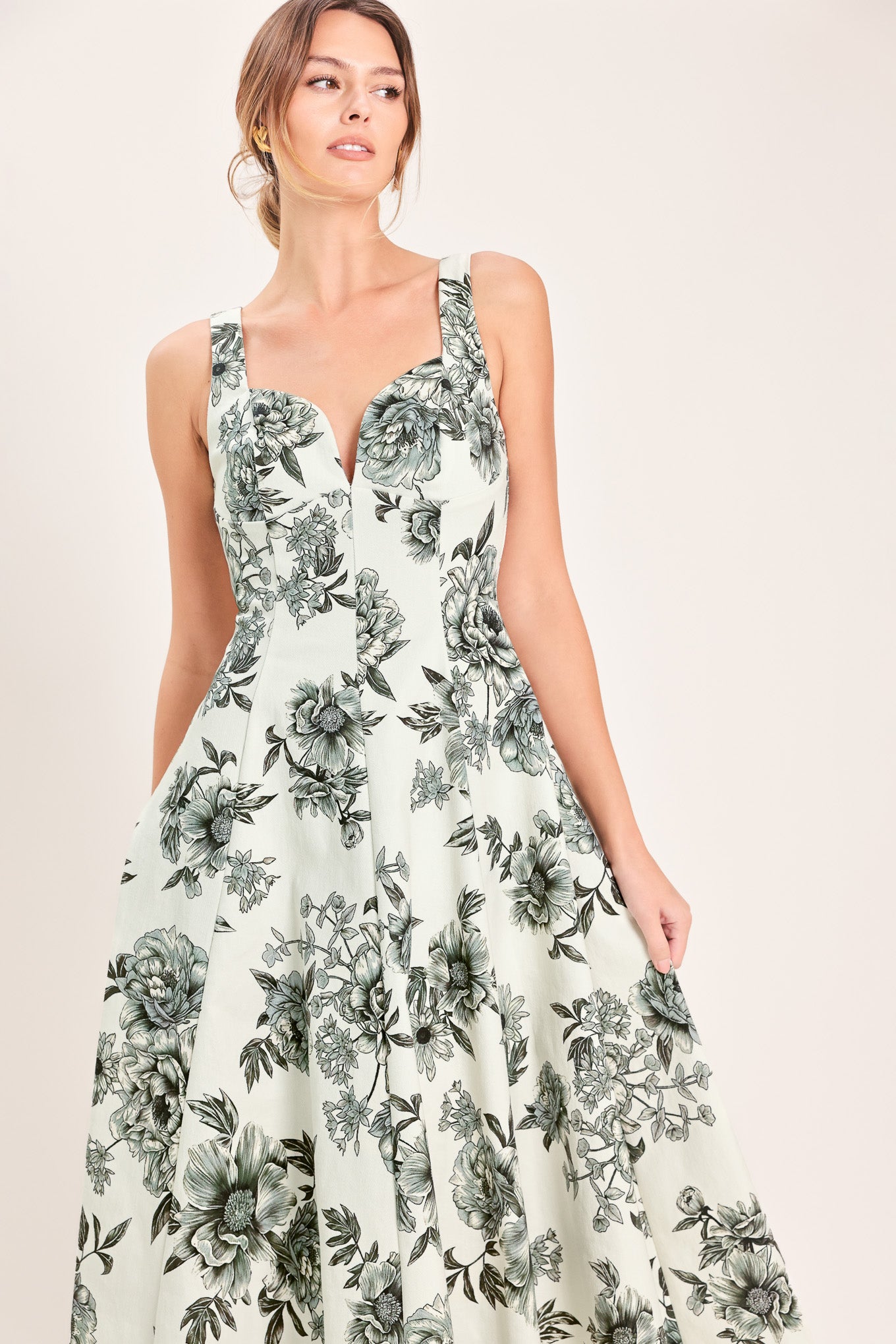 Woman wearing a black and white floral midi dress featuring sweetheart neckline, straps, circle skirt and back zipper closure | Flying Tomato
