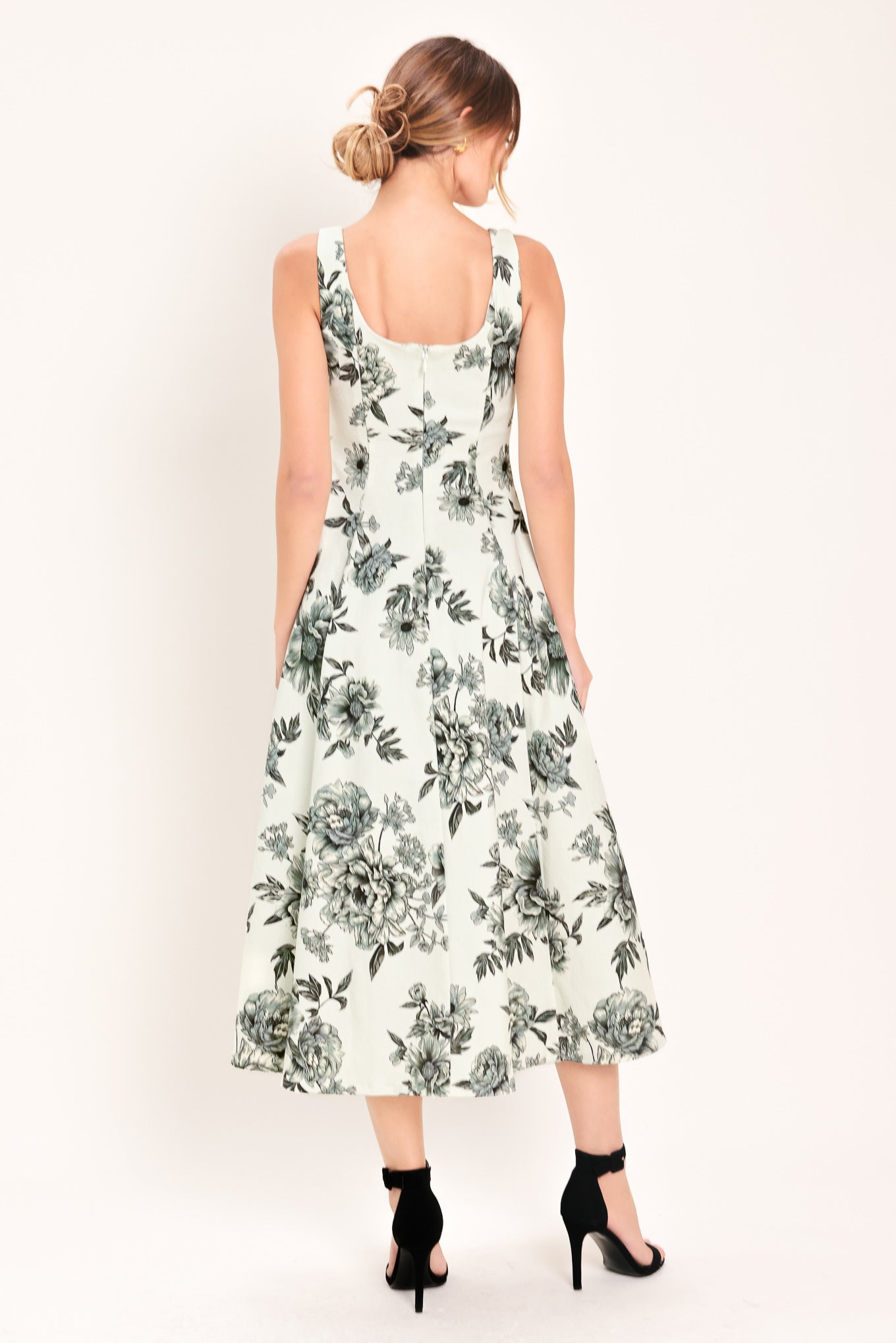 Woman wearing a black and white floral midi dress featuring sweetheart neckline, straps, circle skirt and back zipper closure | Flying Tomato