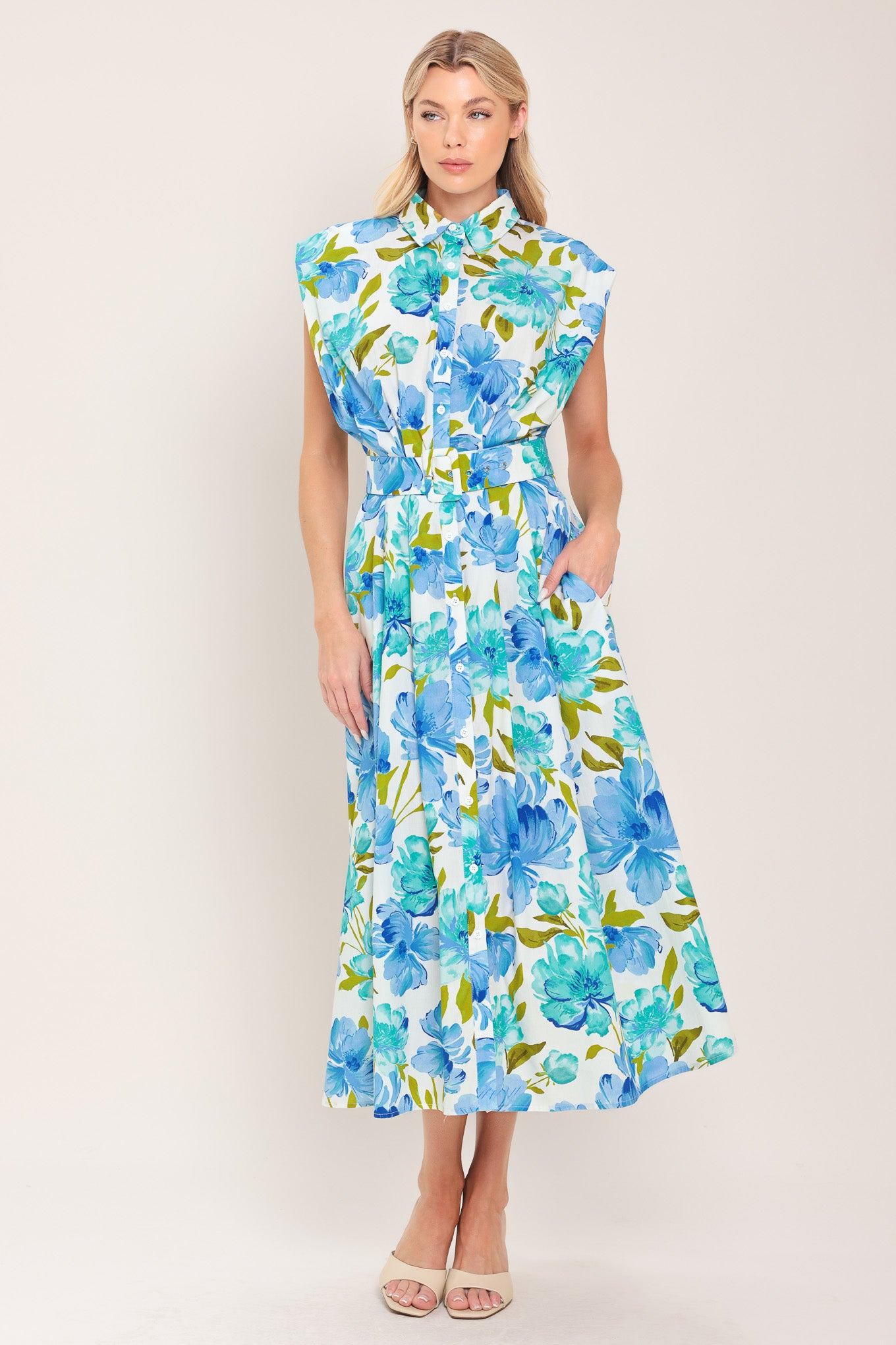 Woman wearing a blue, green, and teal floral midi dress featuring collar, drop shoulder, button down closure, self belt and full skirt | Flying Tomato