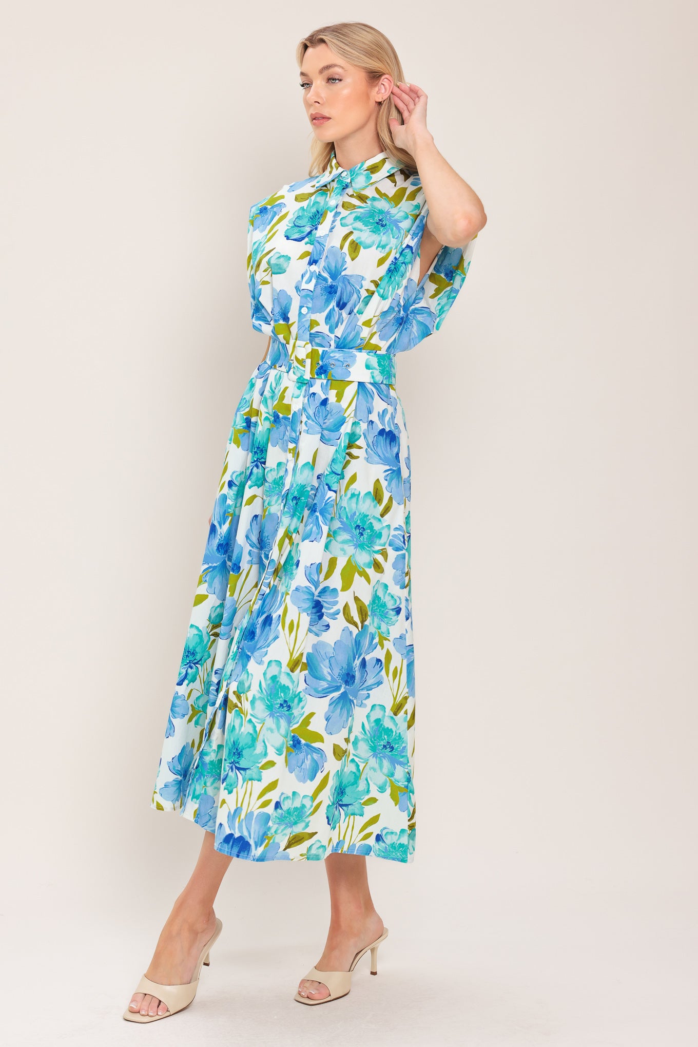 Woman wearing a blue, green, and teal floral midi dress featuring collar, drop shoulder, button down closure, self belt and full skirt | Flying Tomato