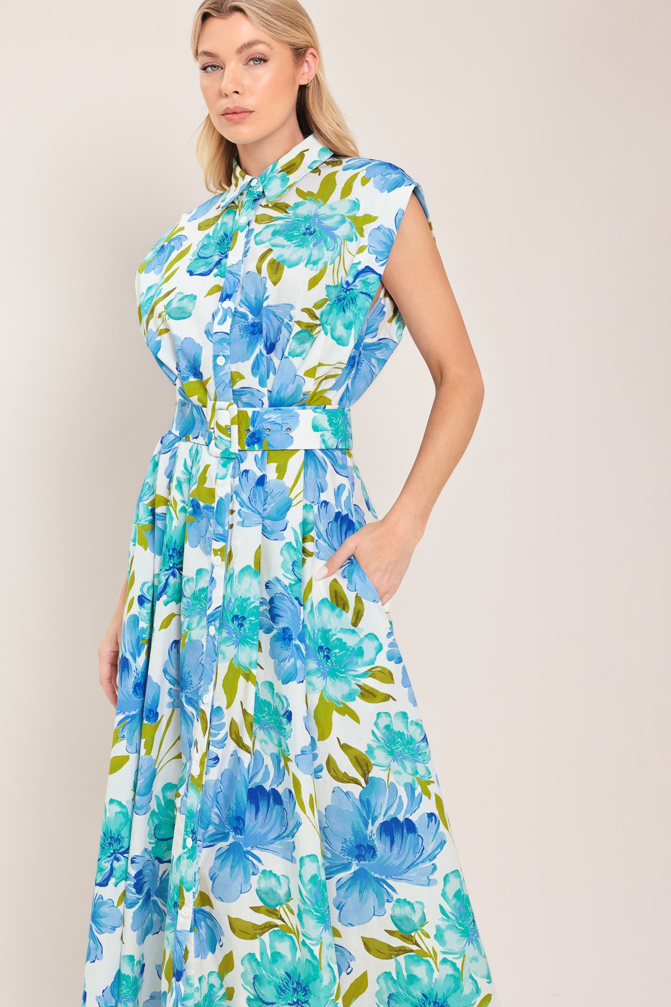 Woman wearing a blue, green, and teal floral midi dress featuring collar, drop shoulder, button down closure, self belt and full skirt | Flying Tomato