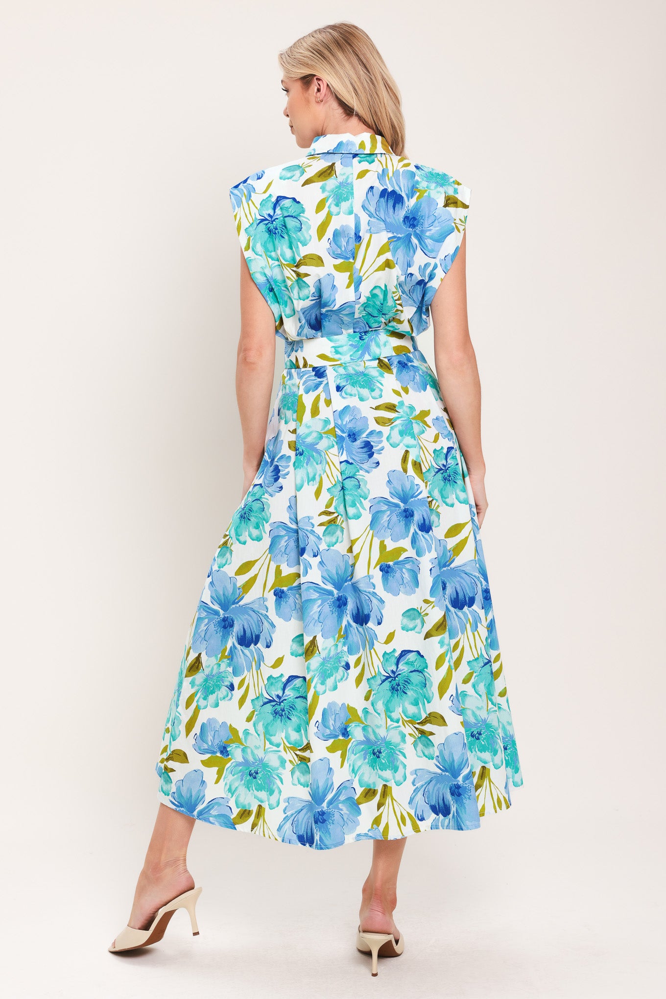 Woman wearing a blue, green, and teal floral midi dress featuring collar, drop shoulder, button down closure, self belt and full skirt | Flying Tomato