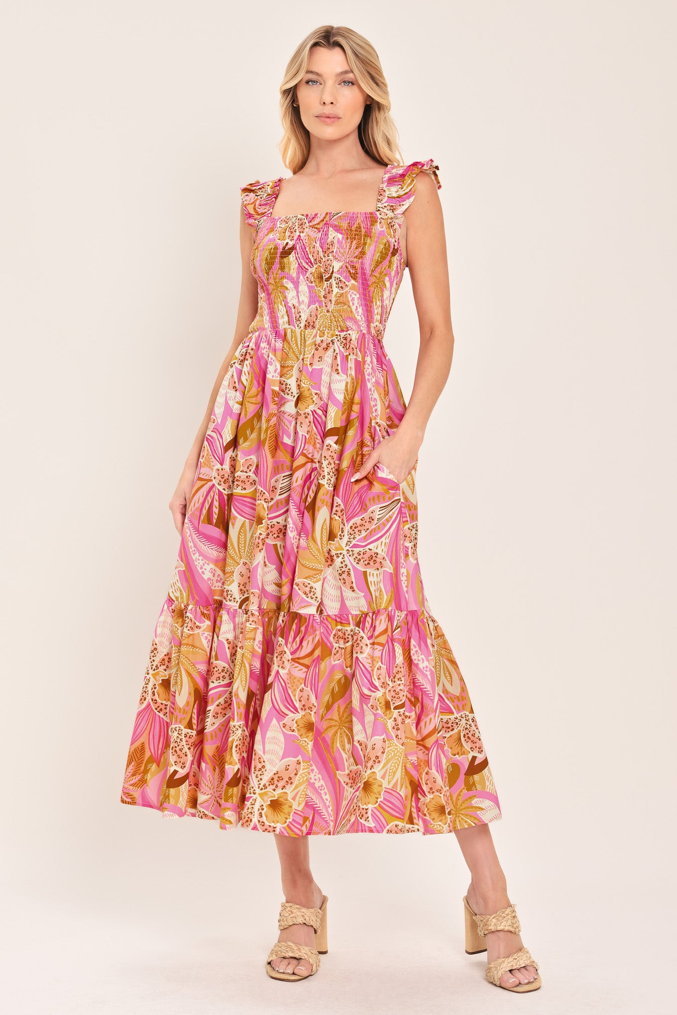 Woman wearing a pink tropical floral midi dress featuring square neckline, ruffle sleeve, smocked bodice and tier skirt | Flying Tomato