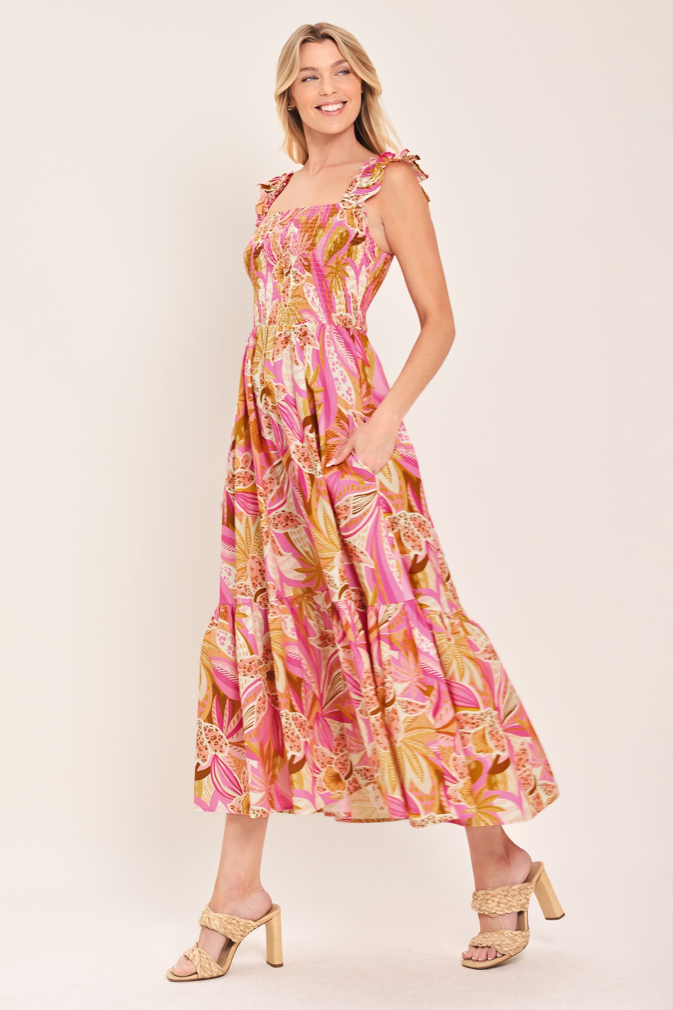 Woman wearing a pink tropical floral midi dress featuring square neckline, ruffle sleeve, smocked bodice and tier skirt | Flying Tomato