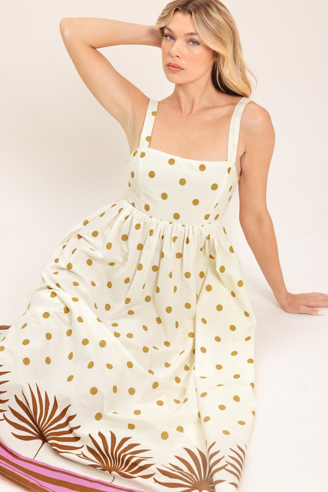 Woman wearing a white midi dress with gold polka dots and brown leaf patterns | Flying Tomato