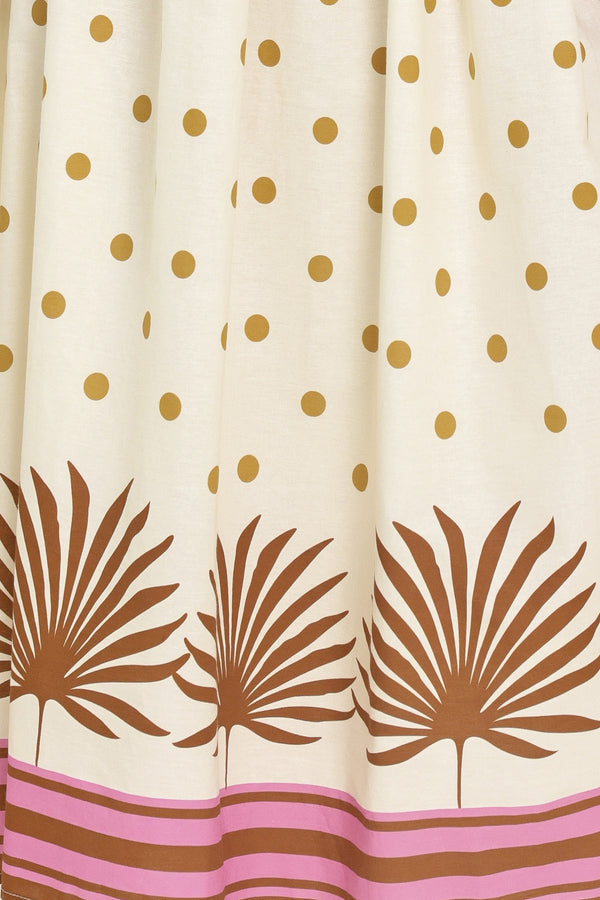 Woman wearing a white midi dress with gold polka dots and brown leaf patterns | Flying Tomato