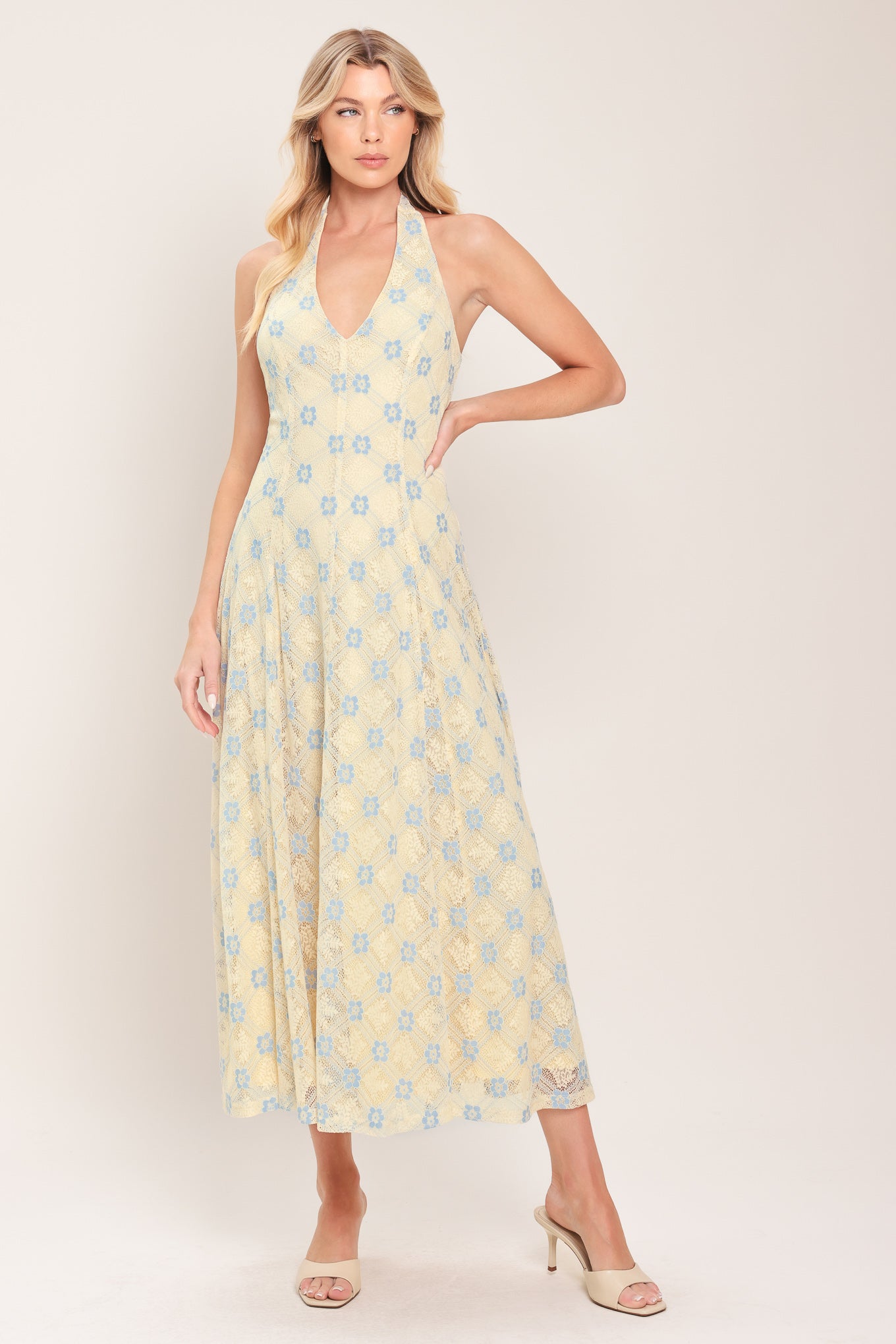 Woman wearing a yellow with blue floral lace midi dress featuring halter neckline, full circle skirt and back zipper closure with back neck tie | Flying Tomato
