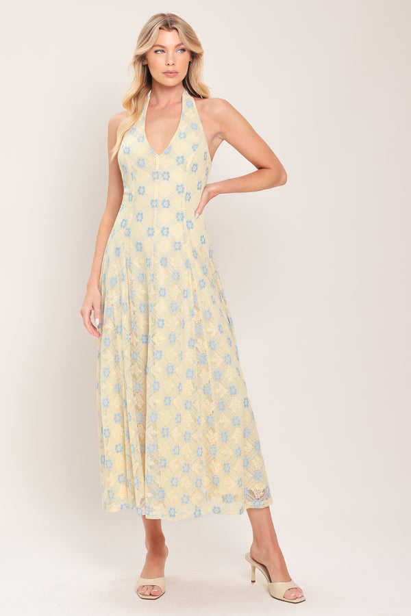 Woman wearing a yellow with blue floral lace midi dress featuring halter neckline, full circle skirt and back zipper closure with back neck tie | Flying Tomato