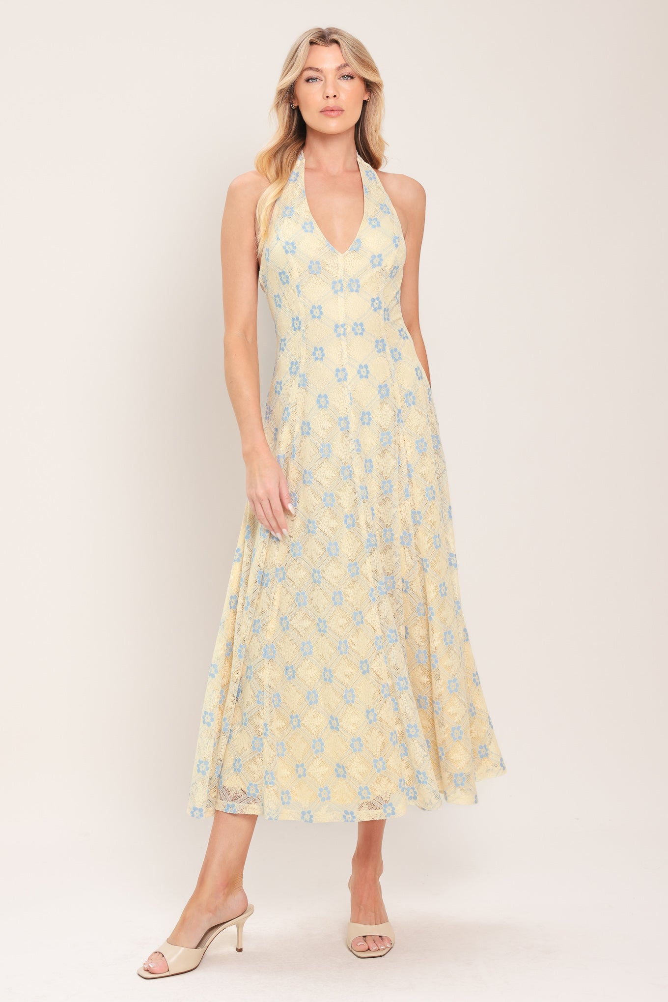 Woman wearing a yellow with blue floral lace midi dress featuring halter neckline, full circle skirt and back zipper closure with back neck tie | Flying Tomato