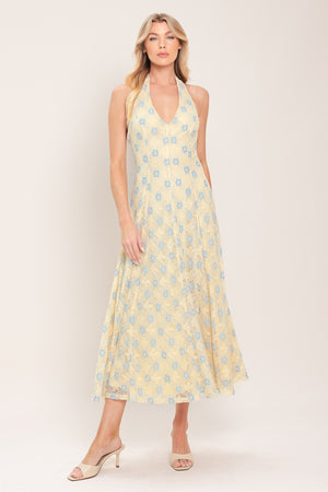 Woman wearing a yellow with blue floral lace midi dress featuring halter neckline, full circle skirt and back zipper closure with back neck tie | Flying Tomato
