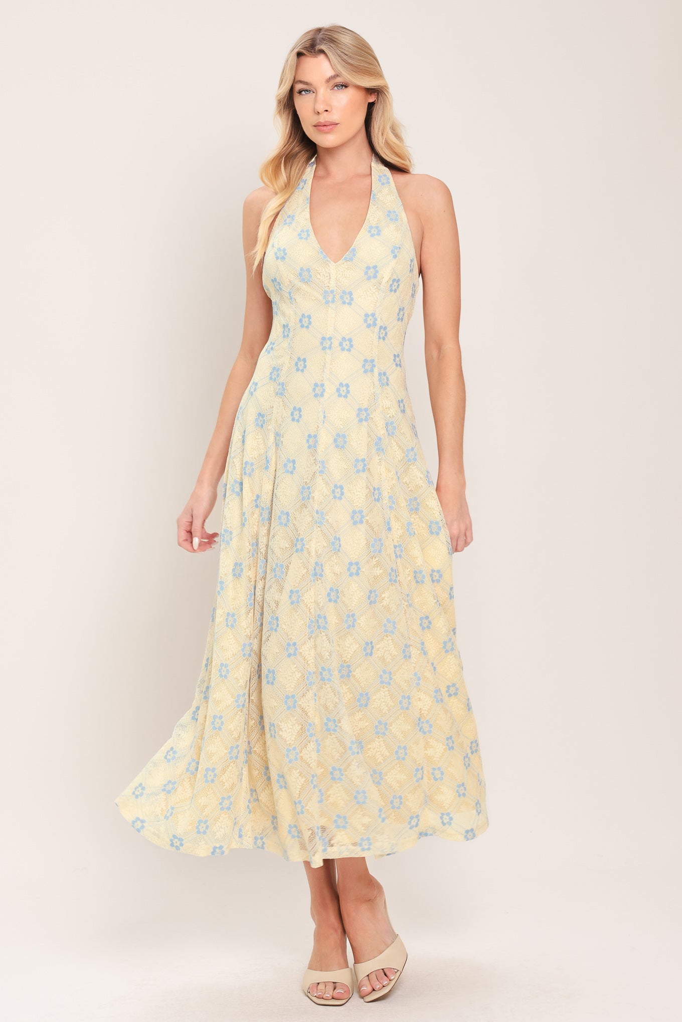 Woman wearing a yellow with blue floral lace midi dress featuring halter neckline, full circle skirt and back zipper closure with back neck tie | Flying Tomato