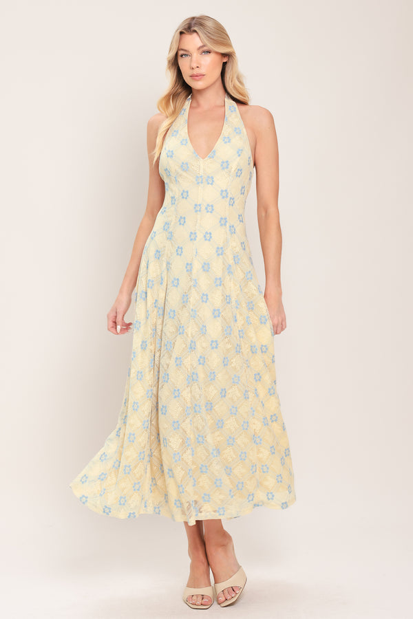 Woman wearing a yellow with blue floral lace midi dress featuring halter neckline, full circle skirt and back zipper closure with back neck tie | Flying Tomato