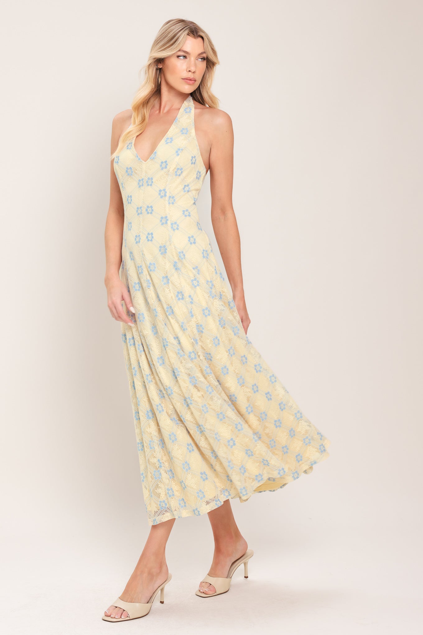 Woman wearing a yellow with blue floral lace midi dress featuring halter neckline, full circle skirt and back zipper closure with back neck tie | Flying Tomato