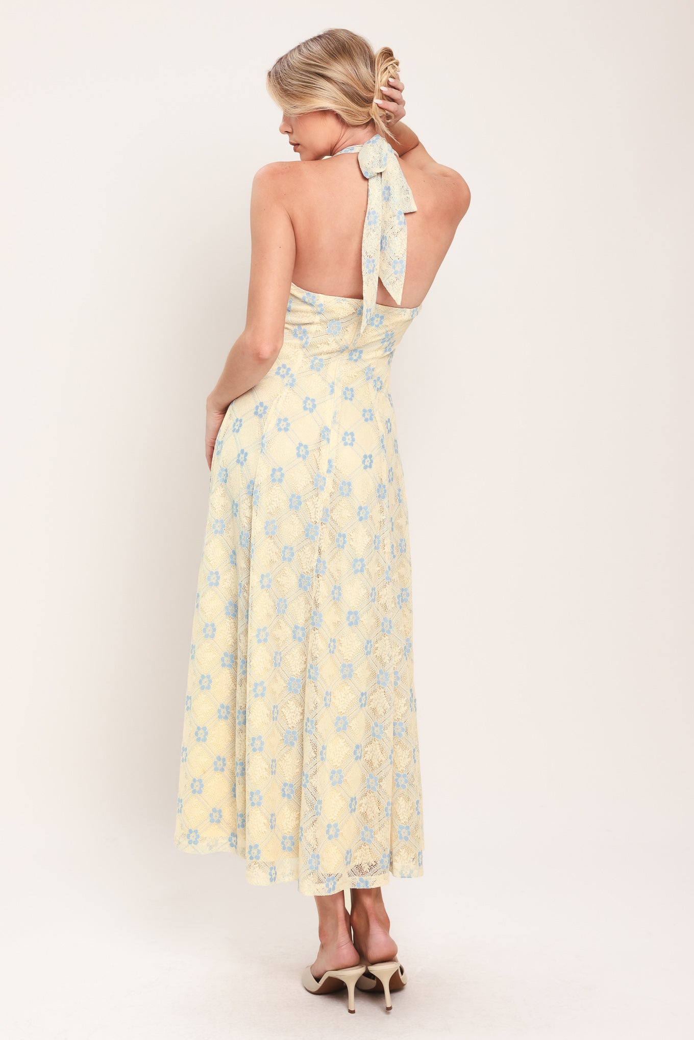 Woman wearing a yellow with blue floral lace midi dress featuring halter neckline, full circle skirt and back zipper closure with back neck tie | Flying Tomato
