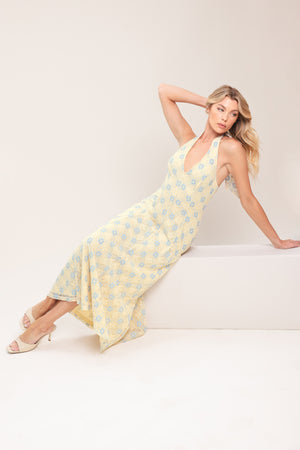 Woman wearing a yellow with blue floral lace midi dress featuring halter neckline, full circle skirt and back zipper closure with back neck tie | Flying Tomato