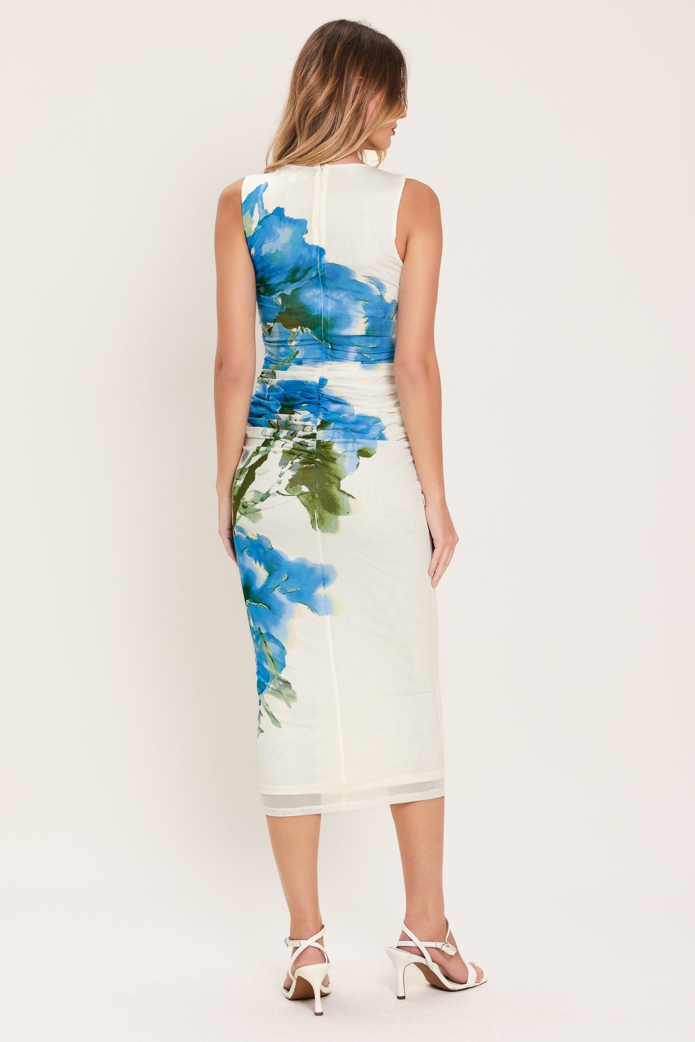 Woman wearing a sleeveless, shirred body power mesh midi dress with blue and green floral patterns | Flying Tomato
