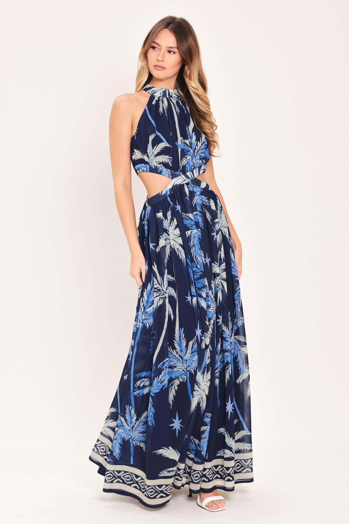 Woman wearing a blue and navy tropical patterned dress with palm trees | Flying Tomato