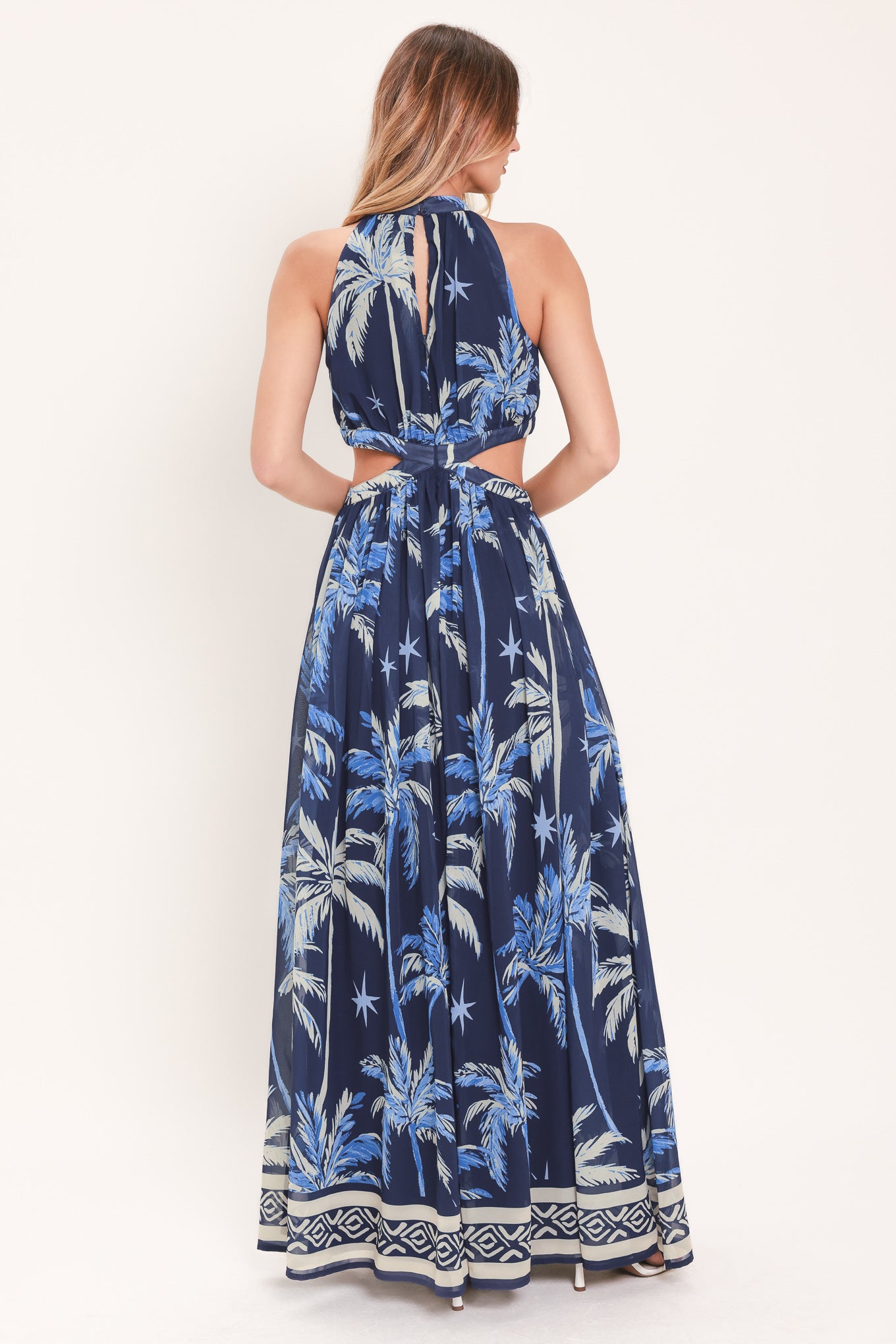 Woman wearing a blue and navy tropical patterned dress with palm trees | Flying Tomato