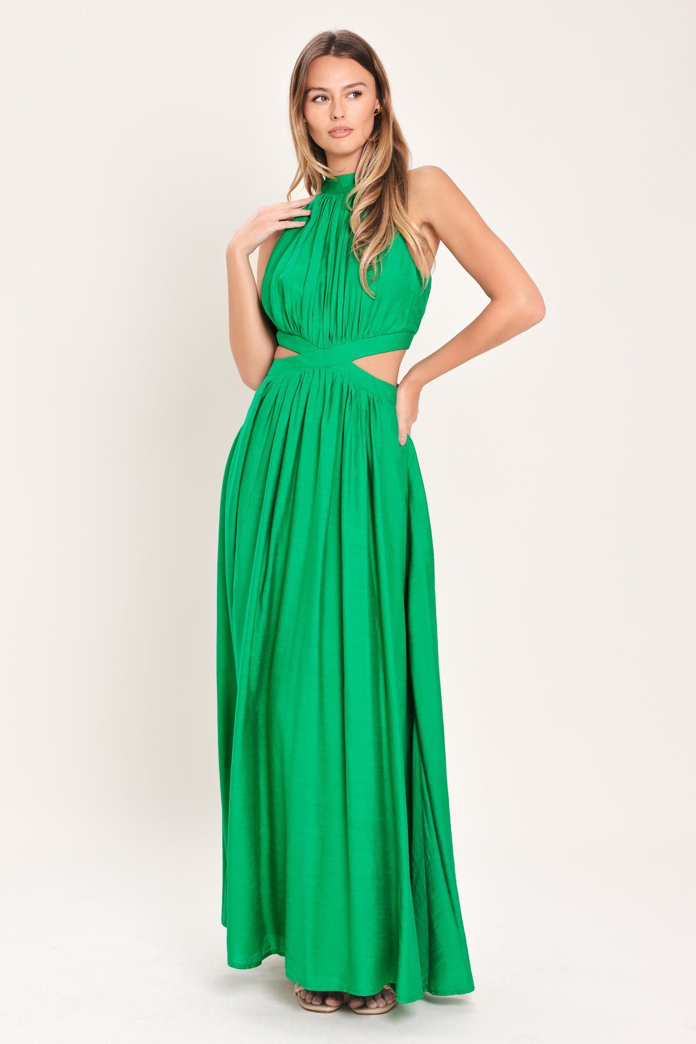 Woman wearing a green maxi dress featuring halter neckline, side cut out and back button/zipper closure | Flying Tomato