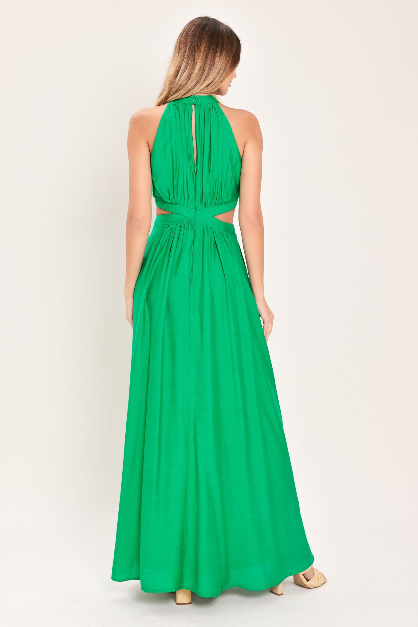Woman wearing a green maxi dress featuring halter neckline, side cut out and back button/zipper closure | Flying Tomato