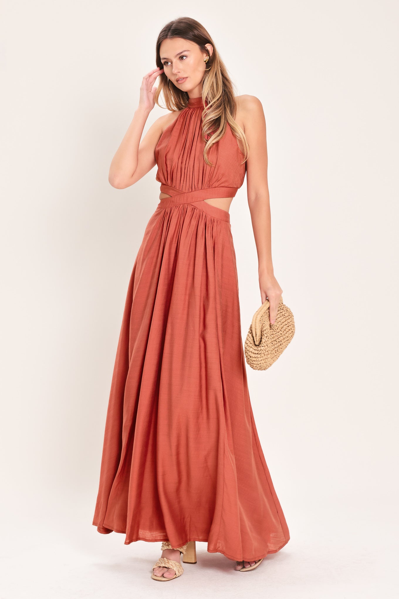 Woman wearing a terracotta maxi dress featuring halter neckline, side cut out and back button/zipper closure | Flying Tomato