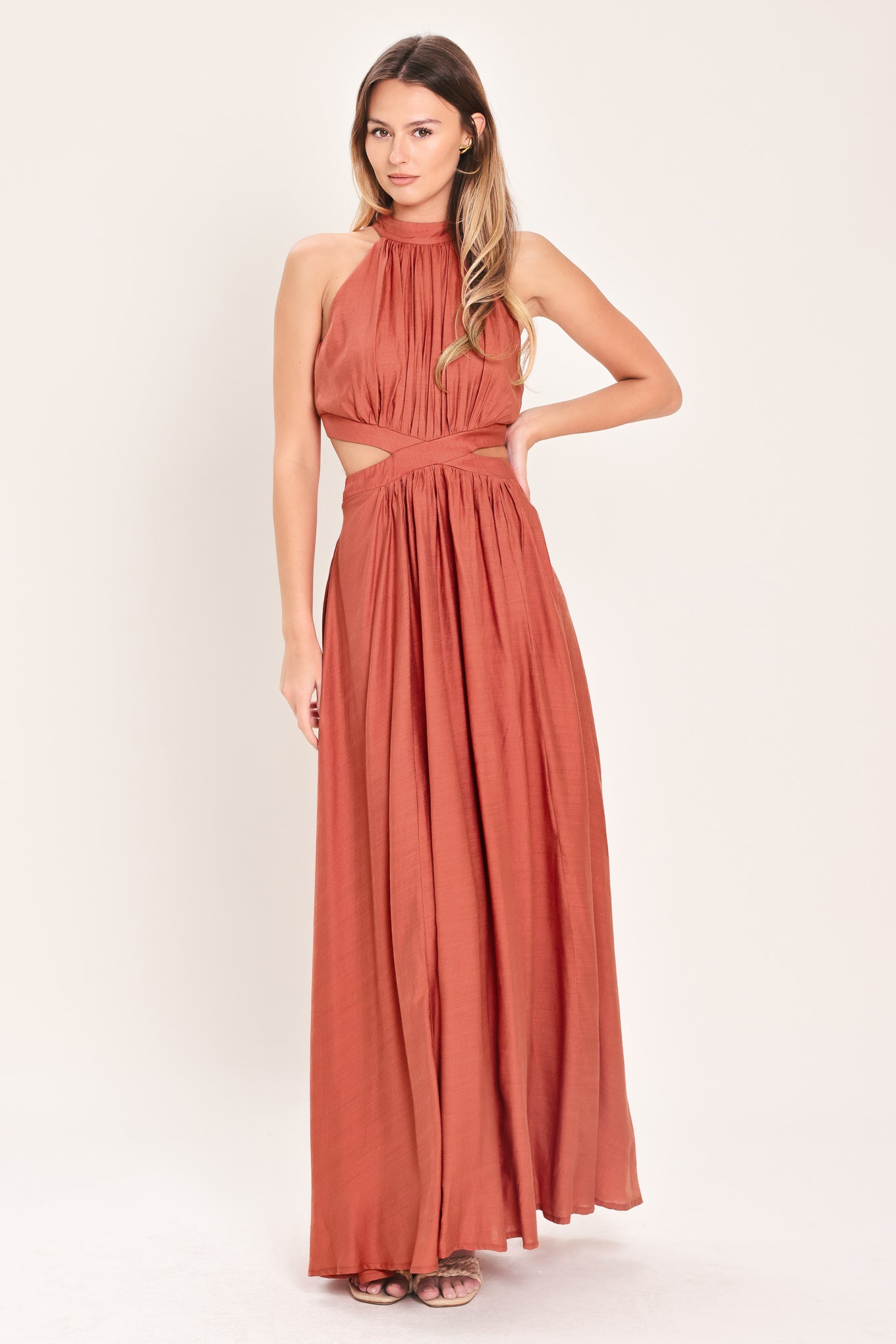 Woman wearing a terracotta maxi dress featuring halter neckline, side cut out and back button/zipper closure | Flying Tomato