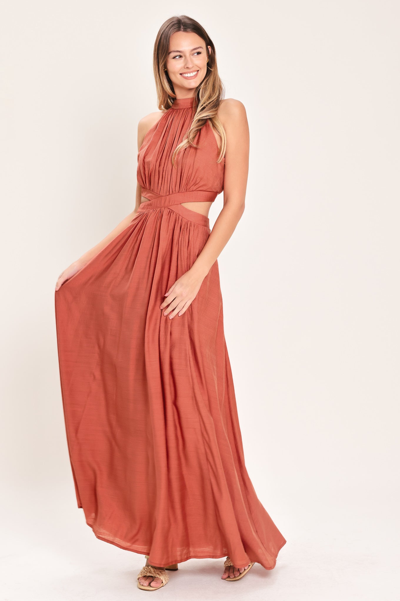 Woman wearing a terracotta maxi dress featuring halter neckline, side cut out and back button/zipper closure | Flying Tomato
