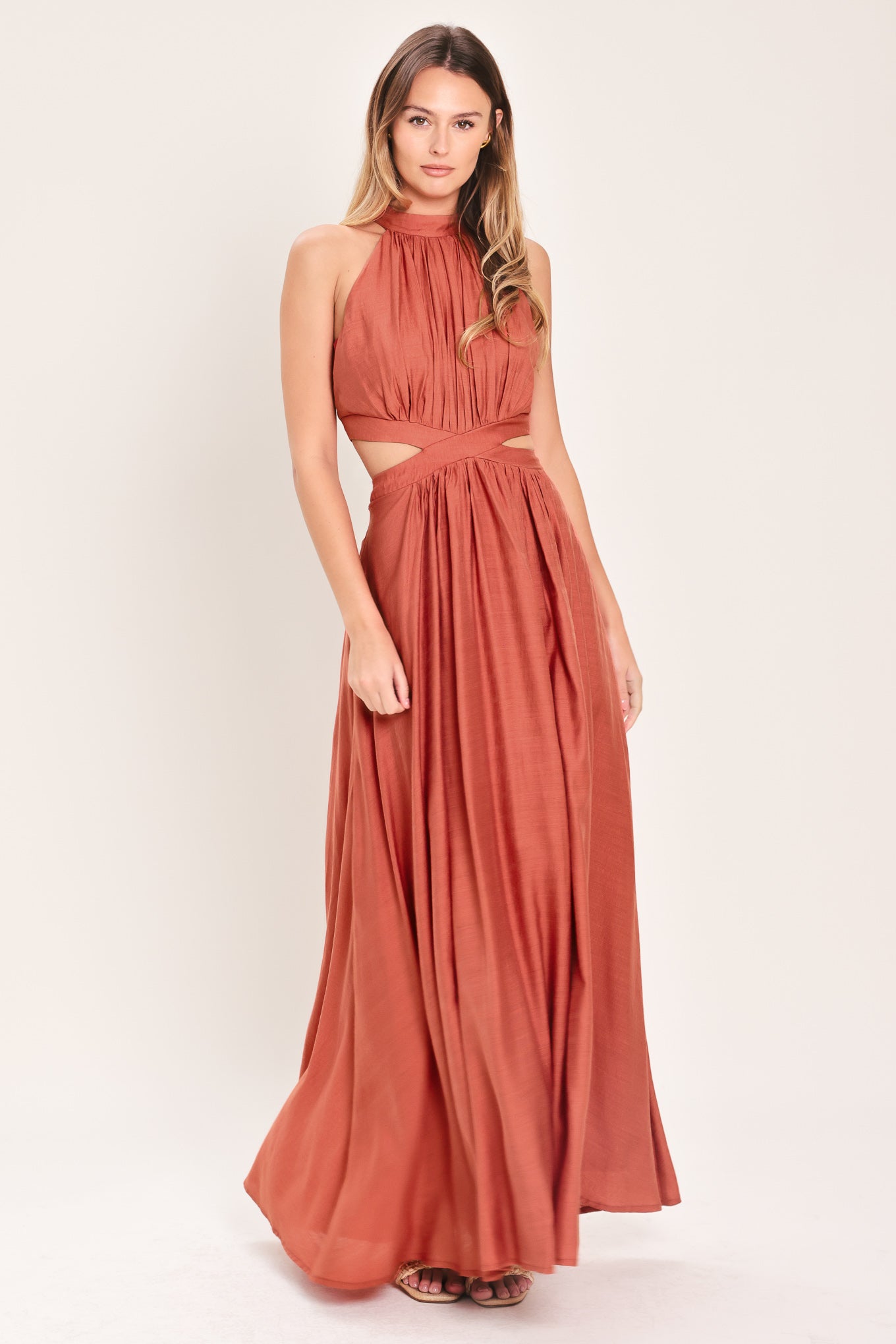 Woman wearing a terracotta maxi dress featuring halter neckline, side cut out and back button/zipper closure | Flying Tomato