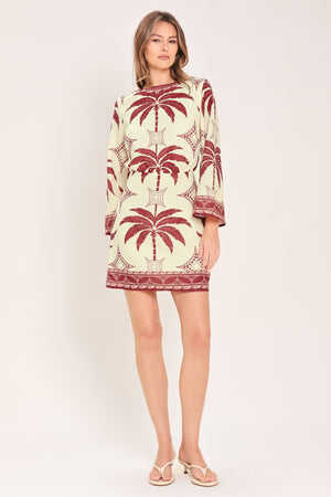 Woman wearing an ivory long sleeve mini dress with maroon palm tree design | Flying Tomato