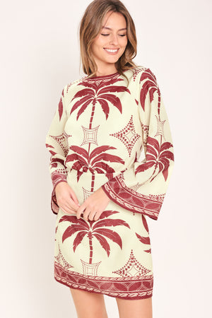 Woman wearing an ivory long sleeve mini dress with maroon palm tree design | Flying Tomato