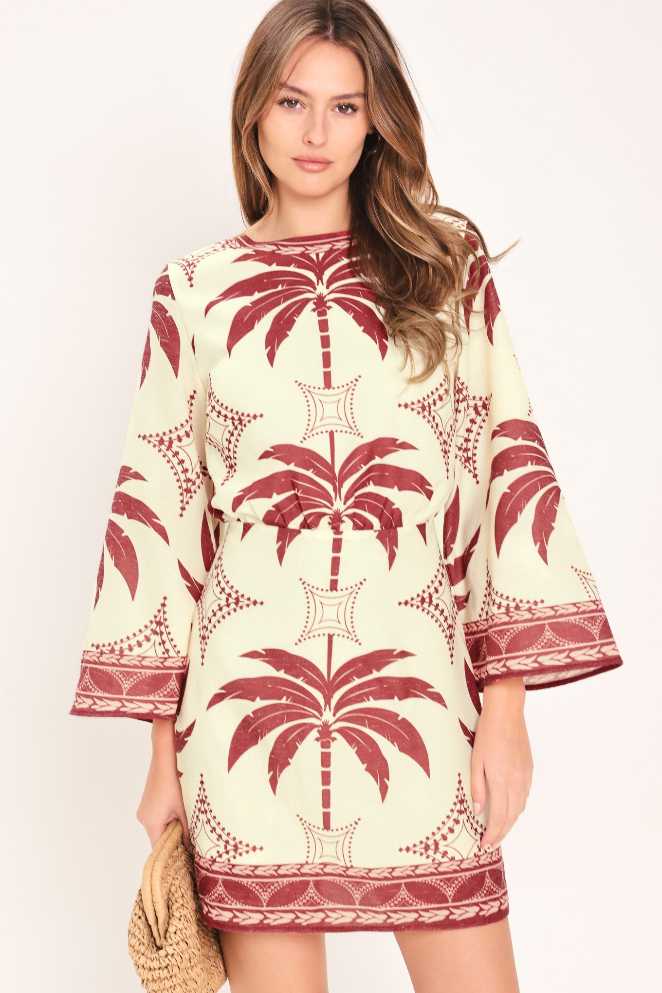 Woman wearing an ivory long sleeve mini dress with maroon palm tree design | Flying Tomato