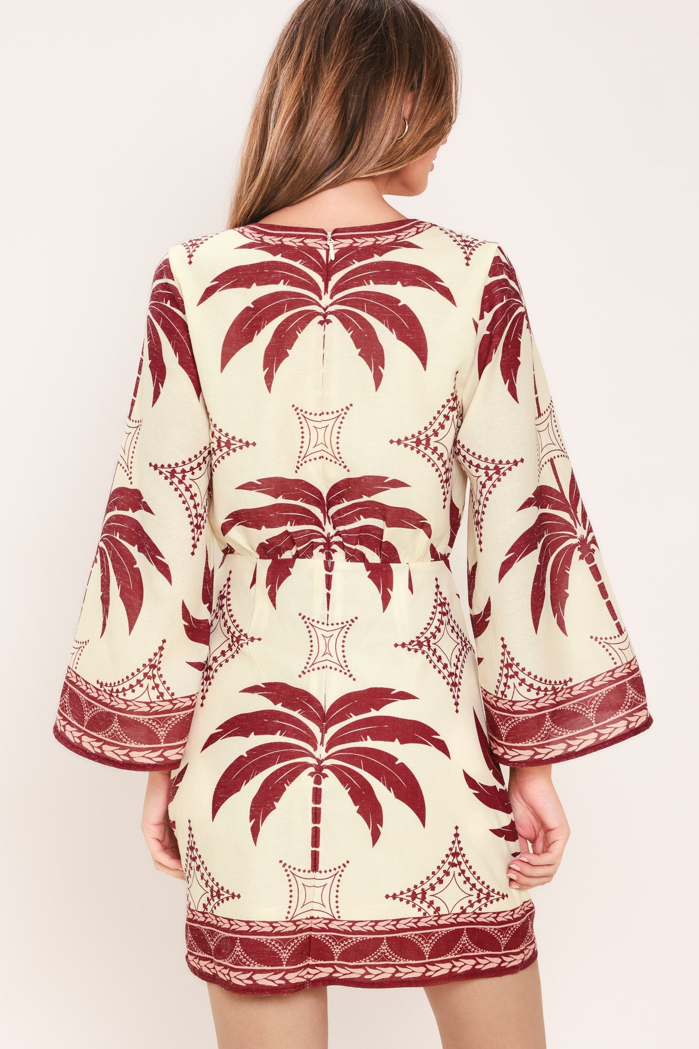 Woman wearing an ivory long sleeve mini dress with maroon palm tree design | Flying Tomato