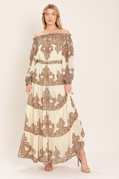 Woman wearing an off-shoulder maxi dress with intricate brown embroidery featuring a smocked back waistband | Flying Tomato