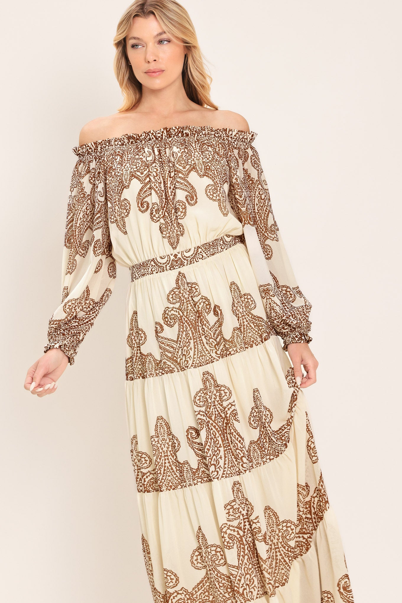 Woman wearing an off-shoulder maxi dress with intricate brown embroidery featuring a smocked back waistband | Flying Tomato