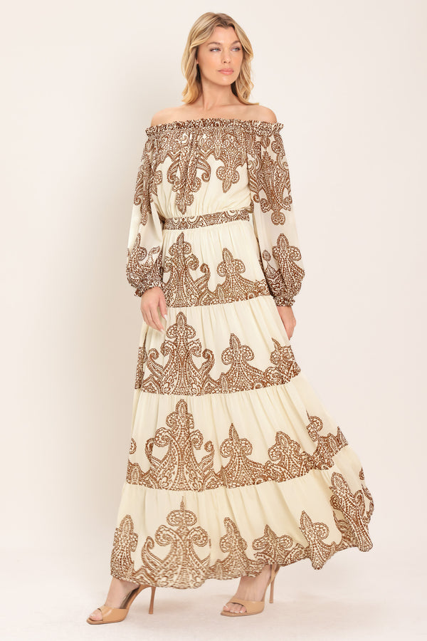 Woman wearing an off-shoulder maxi dress with intricate brown embroidery featuring a smocked back waistband | Flying Tomato