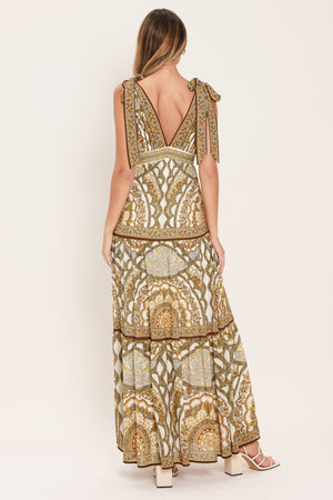 Woman wearing a gold and beige patterned maxi dress featuring front and back V neckline, shoulder ties, smocked waistband and tier skirt | Flying Tomato