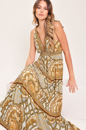 Woman wearing a gold and beige patterned maxi dress featuring front and back V neckline, shoulder ties, smocked waistband and tier skirt | Flying Tomato