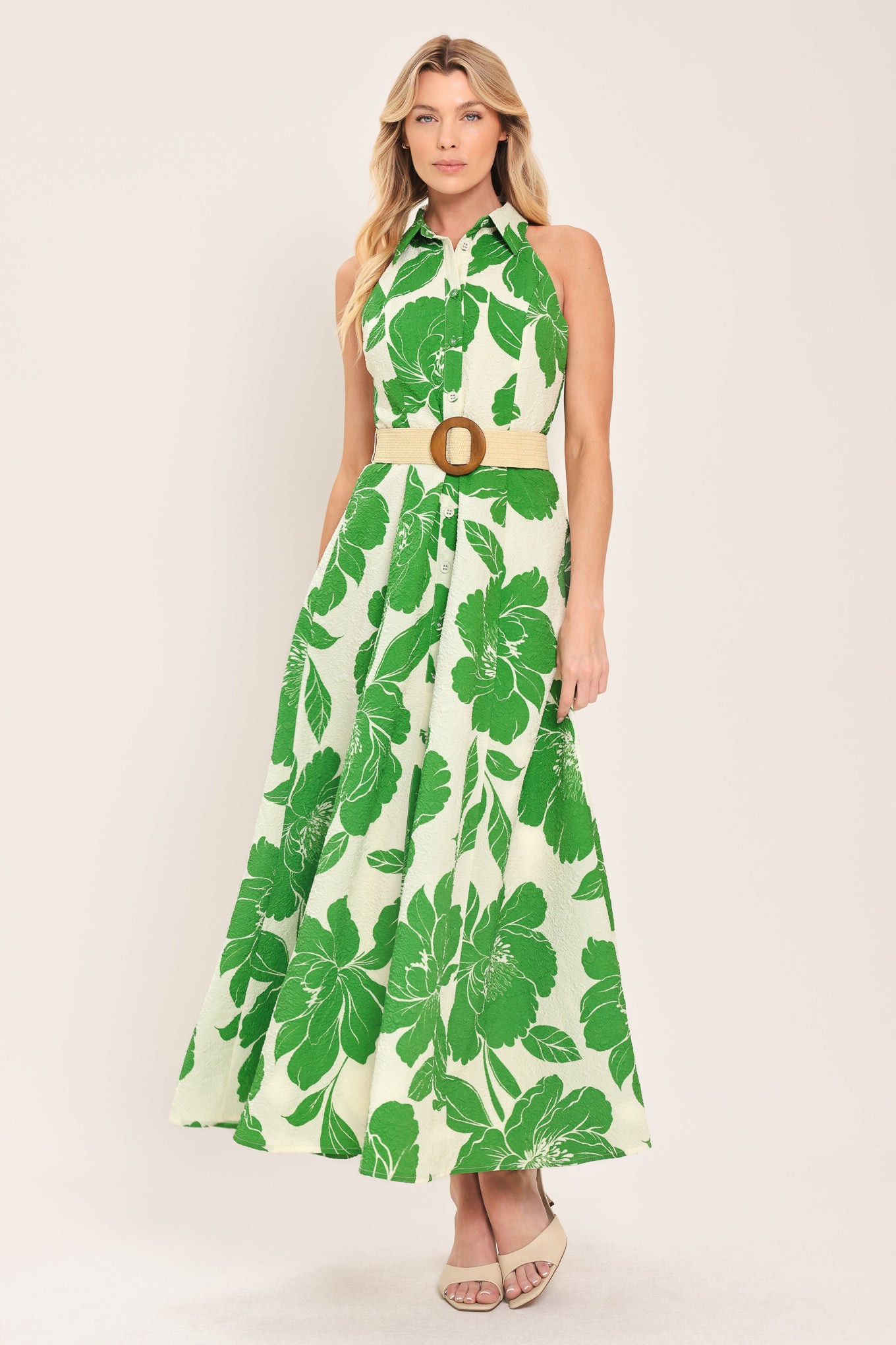 Woman wearing a sleeveless green floral midi dress featuring collar, front button down, contrasting belt and full skirt | Flying Tomato