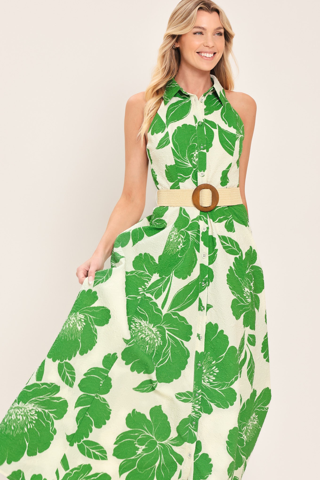 Woman wearing a sleeveless green floral midi dress featuring collar, front button down, contrasting belt and full skirt | Flying Tomato