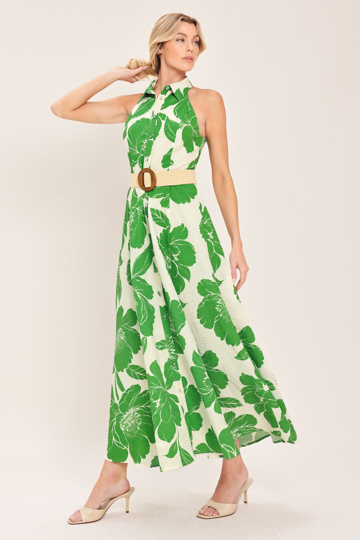Woman wearing a sleeveless green floral midi dress featuring collar, front button down, contrasting belt and full skirt | Flying Tomato