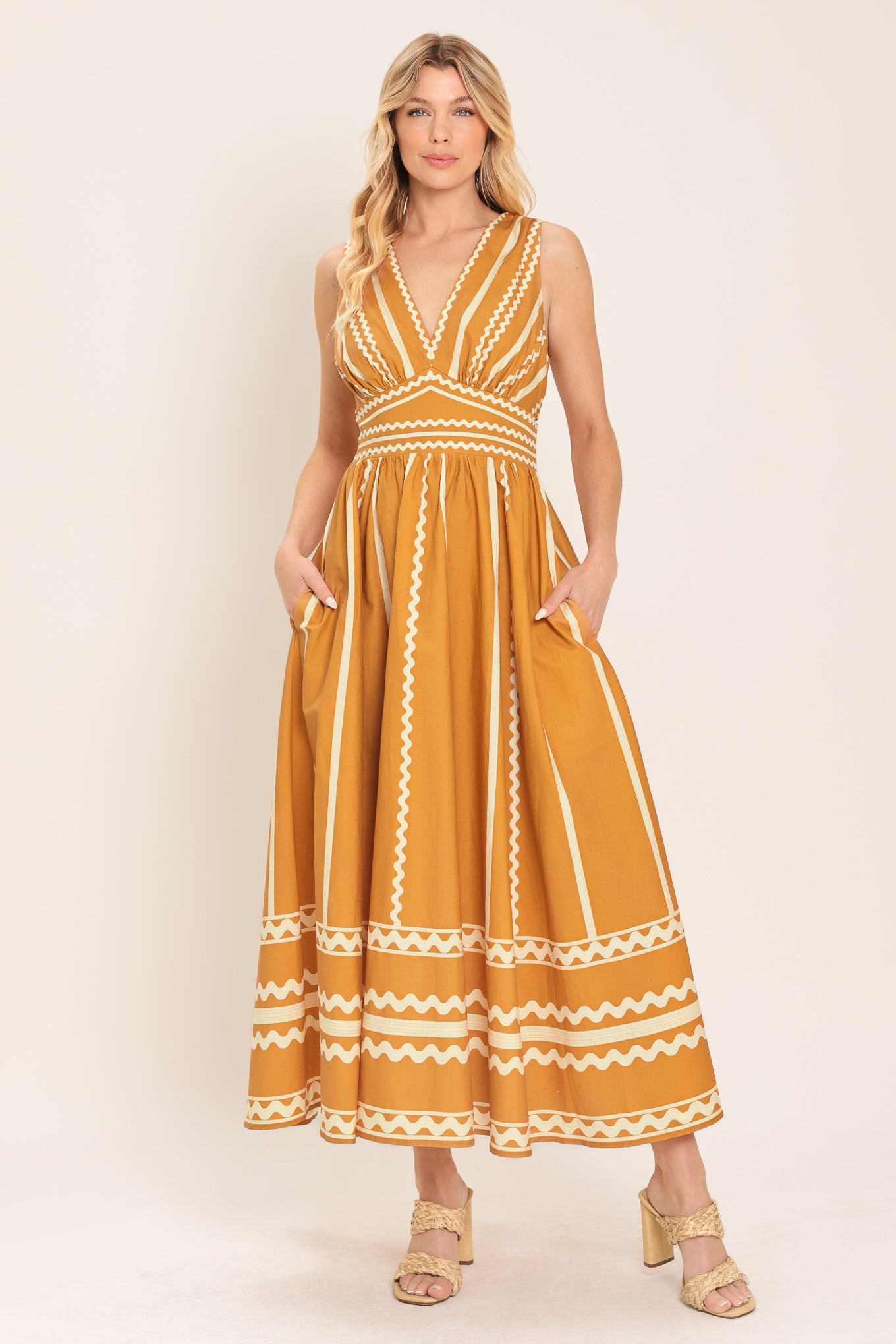 Woman wearing a mustard yellow midi dress with white patterns featuring V neckline, sleeveless, waist yoke, full skirt and smocked back waistband | Flying Tomato