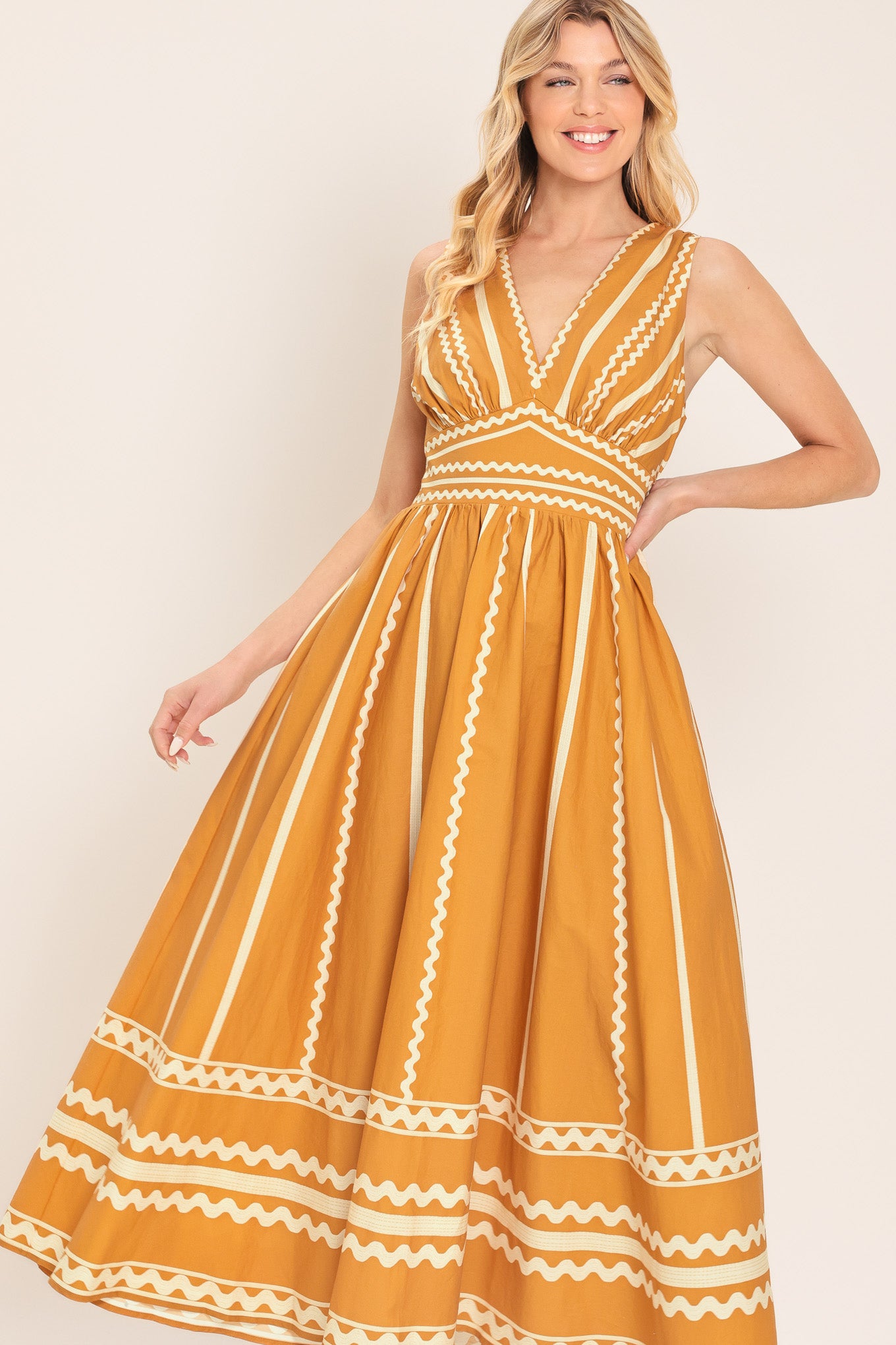 Woman wearing a mustard yellow midi dress with white patterns featuring V neckline, sleeveless, waist yoke, full skirt and smocked back waistband | Flying Tomato