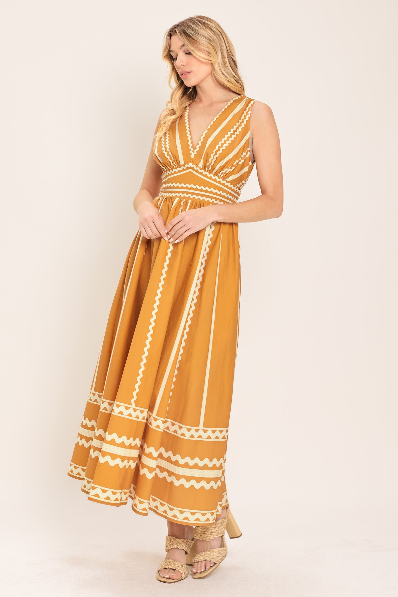 Woman wearing a mustard yellow midi dress with white patterns featuring V neckline, sleeveless, waist yoke, full skirt and smocked back waistband | Flying Tomato